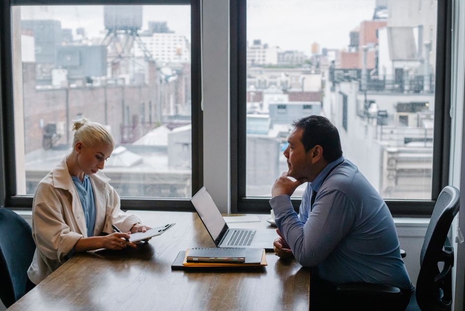 Two colleagues talking at a table by a window